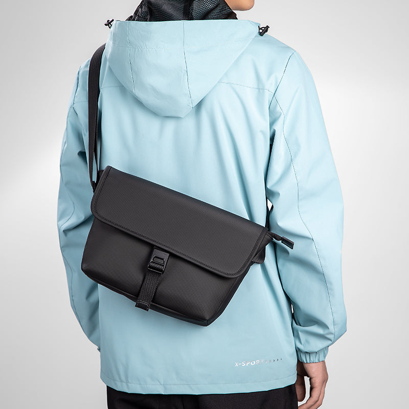 Black crossbody bag on model in light blue jacket - Mark Ryden Global travel essential
