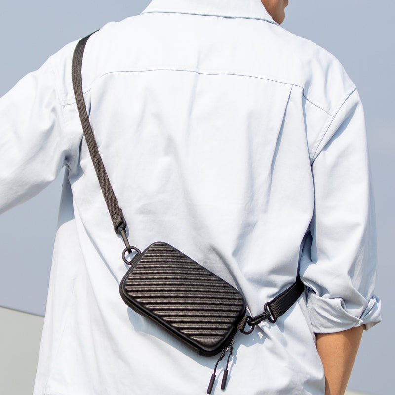 Black ribbed small crossbody purse with adjustable strap, worn by person in white shirt, ideal for travel comfort.