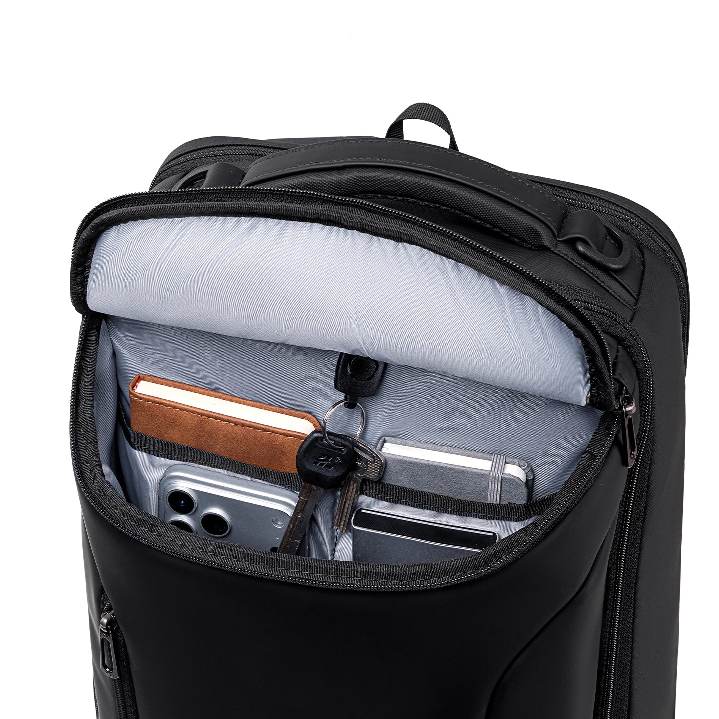 Black MarkRyden Compacto Pro backpack with open main compartment showing gray interior holding smartphone, notebook, keys, and small accessories—futuristic design, large capacity for modern daily use.