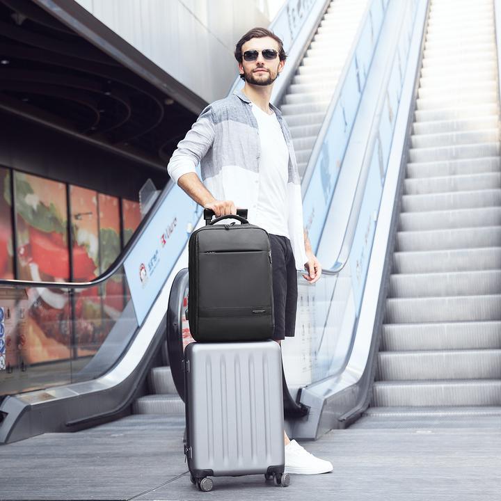 MarkRyden Global black anti-theft backpack on silver suitcase near mall escalator
