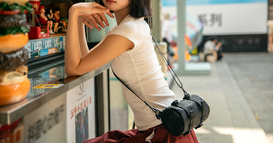 Woman in white top and red pants carrying a black Mark Ryden anti-theft crossbody bag with adjustable strap at a Florence outdoor café.