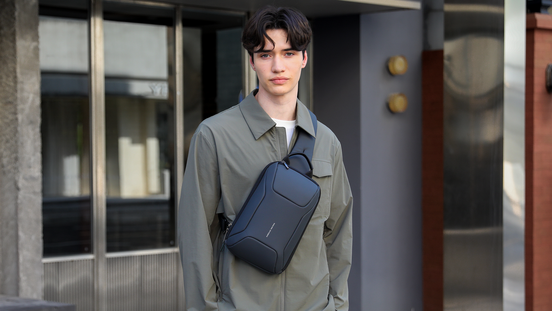 Dark blue Mark Ryden anti-theft crossbody bag with sleek design, worn by a person in a green jacket.