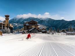 Skier in red jacket on snowy Colorado ski slope near mountain lodge | Ski gear guide