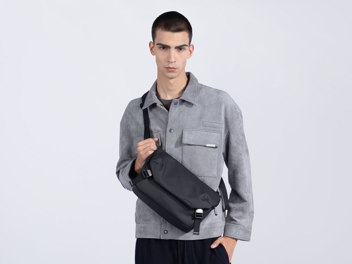 Model in gray jacket wearing Mark Ryden black anti-theft messenger bag
