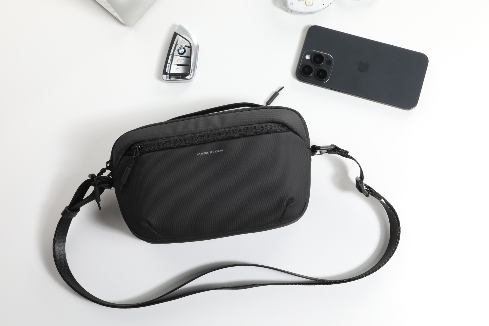 Black Mark Ryden crossbody bag with shoulder strap, travel essentials shown