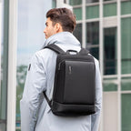 Man in gray coat wearing MarkRyden dual-material lightweight backpack near city building