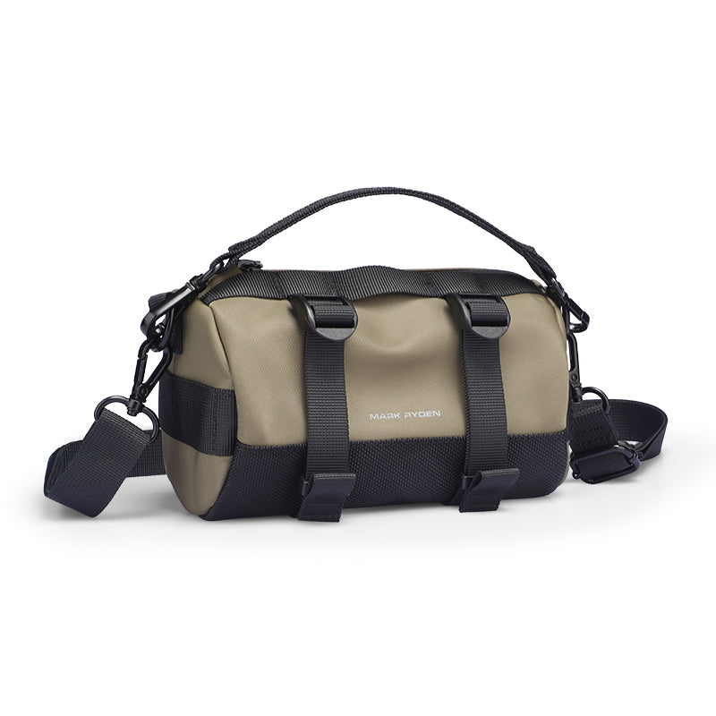 MotoBarrel Cylinder Crossbody Bag in tan and black durable fabric with adjustable straps, buckles, and Mark Ryden logo for modern travelers.