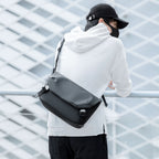 Mark Ryden Global: Black leather waterproof messenger bag on person in white hoodie
