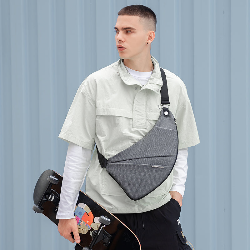 Gray anti-theft chest bag with black strap worn by modern urban traveler with skateboard