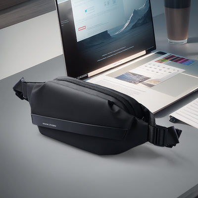 Elegant black Peiano crossbody bag with Mark Ryden logo, made of Oxford material, lightweight and waterproof, displayed on a desk with laptop and monitor.