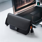 Mark Ryden Global black business casual crossbody bag with buckle on desk near laptop