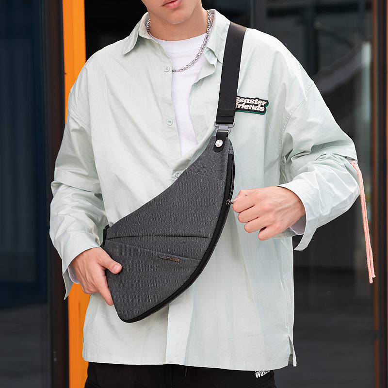 Dark gray ChestFlex chest bag with adjustable strap, worn by model in light shirt - MarkRyden Global