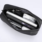 Black portable large capacity traveling toiletries bag with zippered closure, holding power bank, cables, phone, and earbuds.