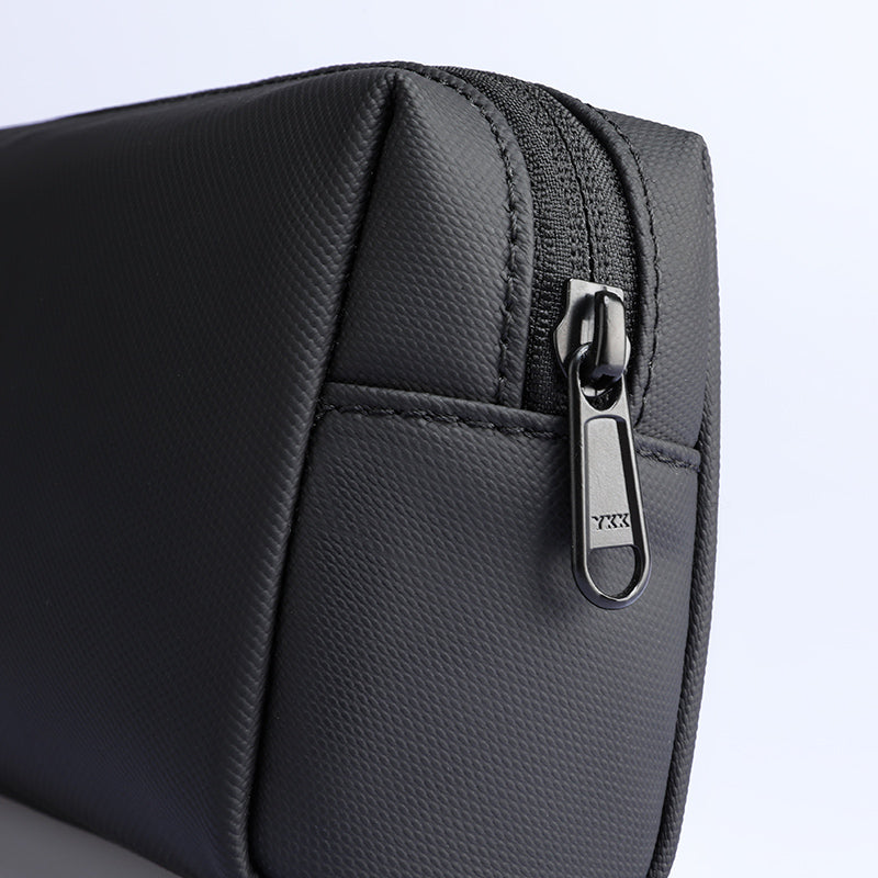 Black portable large capacity traveling toiletries bag with textured exterior, front pocket, and metal zipper pull.