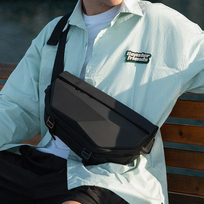 Black waterproof scratch-resistant Diamond Facets crossbody bag worn by modern traveler on bench