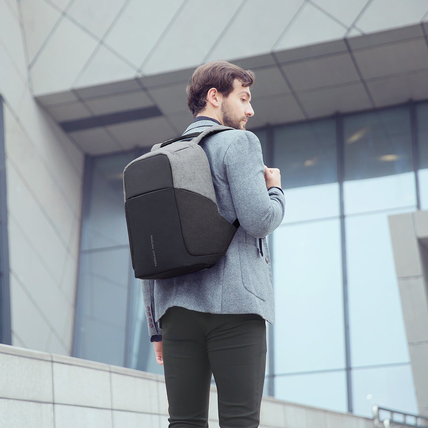 Mark Ryden gray/black anti-theft USB backpack worn by man near modern building