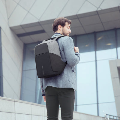 Mark Ryden gray/black anti-theft USB backpack worn by man near modern building