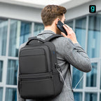 Black Mark Ryden Fady 2nd Gen lightweight laptop backpack with USB charging port and anti-theft pocket, worn by a person with a charging cable connected.