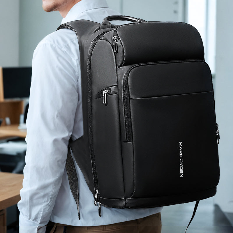 Black Mark Ryden Compacto versatile spacious carry-on laptop backpack with multiple zippered compartments, worn in office setting for 15.6/17.3 inch laptops.