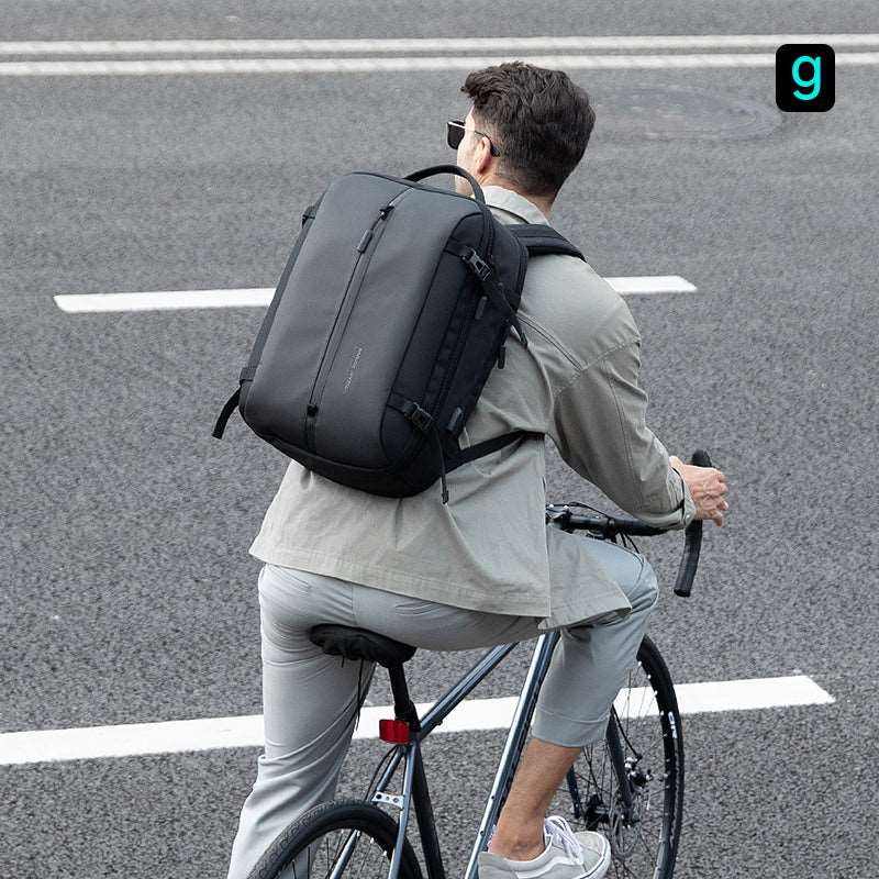 Man cycling with Mark Ryden black smart USB laptop backpack on city road