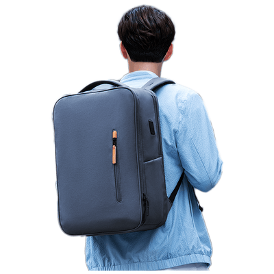 Dark gray Urbanity City Commuter Oxford laptop backpack with front zip pocket (tan accent) and USB port, worn by a person in light blue shirt for urban commuting.