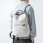 Summer Mist cool ultra-light backpack in light gray with black accents, worn by a person in a gray sweater, featuring a front pocket and adjustable straps.