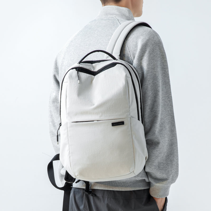 Summer Mist cool ultra-light backpack in light gray with black accents, worn by a person in a gray sweater, featuring a front pocket and adjustable straps.
