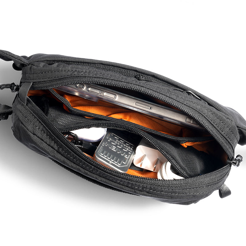 Mark Ryden Global's black anti-theft AeroSling crossbody bag with orange interior holding travel gear