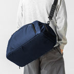 Dark blue TripVault travel duffel bag with separate shoe compartment, designed for gym and travel, carried over shoulder.