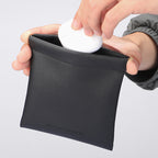 Mark Ryden black leather coin pouch securing white item - modern travel accessory