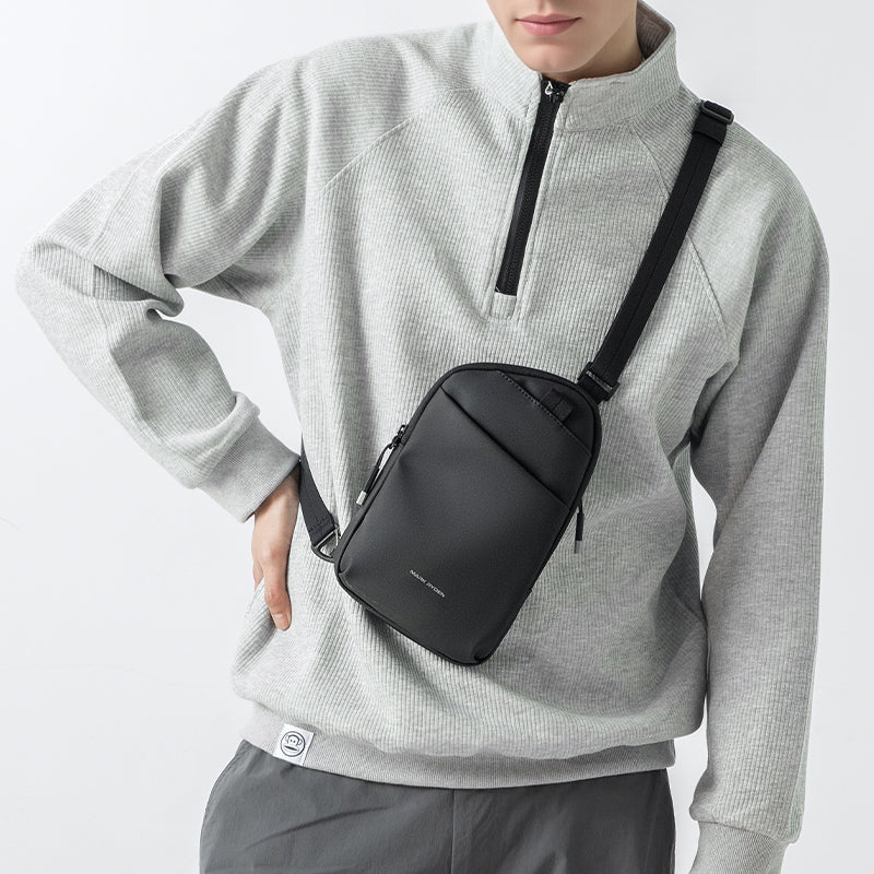 Mark Ryden Global ProCarry black anti-theft sling bag on model in gray sweater