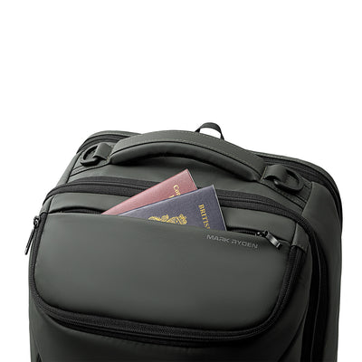 Dark gray Mark Ryden Compacto Pro backpack with front zip pocket holding two passports, featuring durable zippers and ergonomic handle.