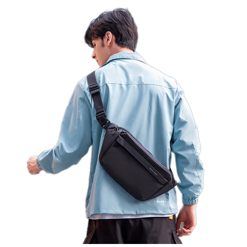 Mark Ryden Global waterproof black crossbody bag on model in light blue jacket - everyday travel bag